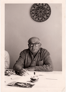 Foto von Emil Behr, Keyvisual und Postermotiv der Ausstellung. Emil Behr sitzt an seinem Schreibtisch.